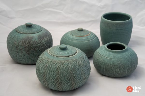 A group of five handmade stoneware jars and vases in a copper-patina matt glaze with various textured finishes.